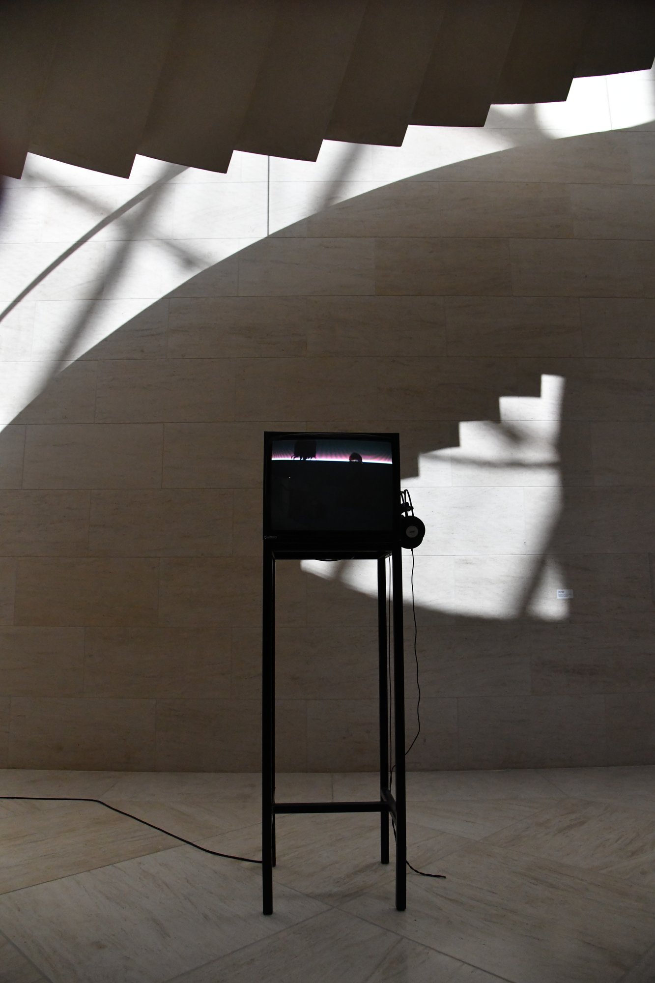 a small screen on a stand in a curved concrete room