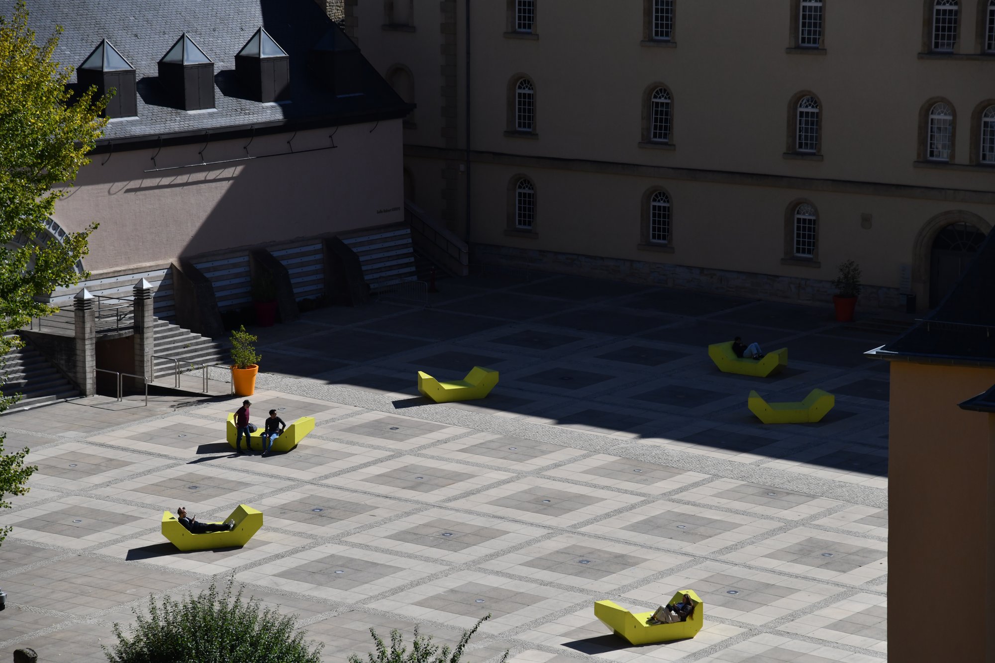 a paved square with yellow loungers, seen from above