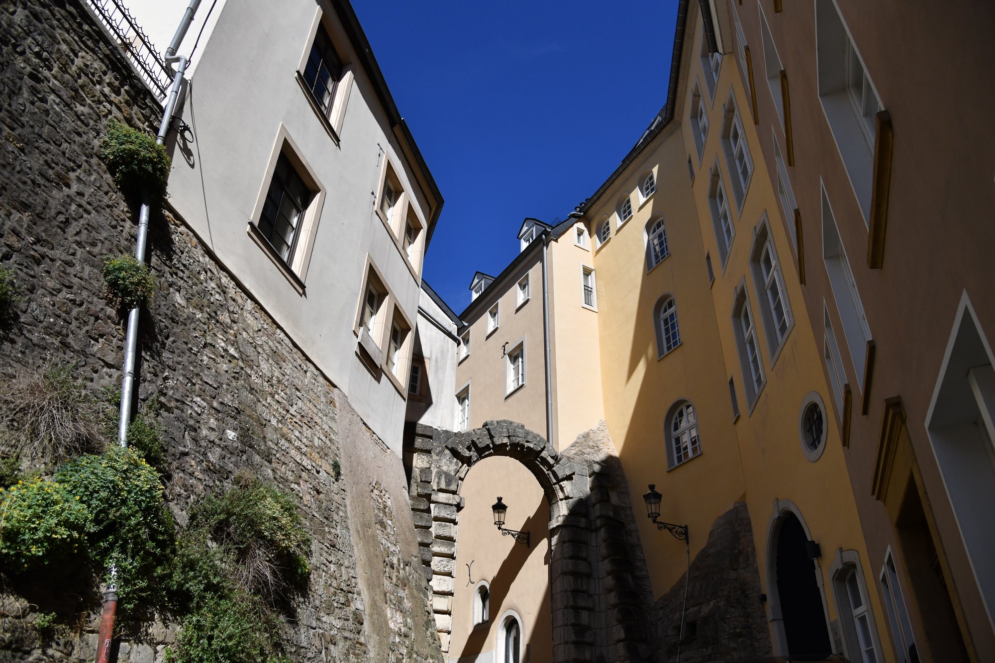 a narrow street of yellow houses and a stone archway