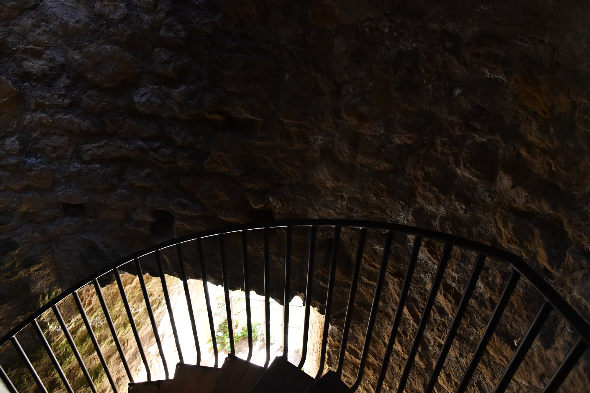 a spiral staircase railing inside a stone wall